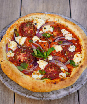 Pizza maison aux oignons rouges, salakis, tomates, basilic, origan